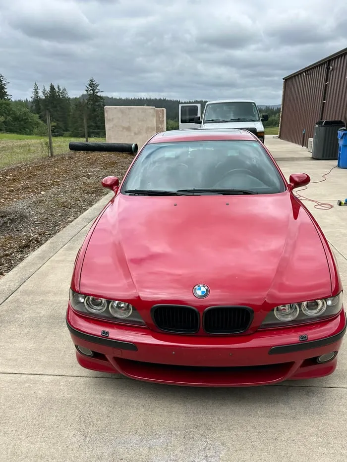 Red BMW E39 M5 photographed head-on on a gravel driveway