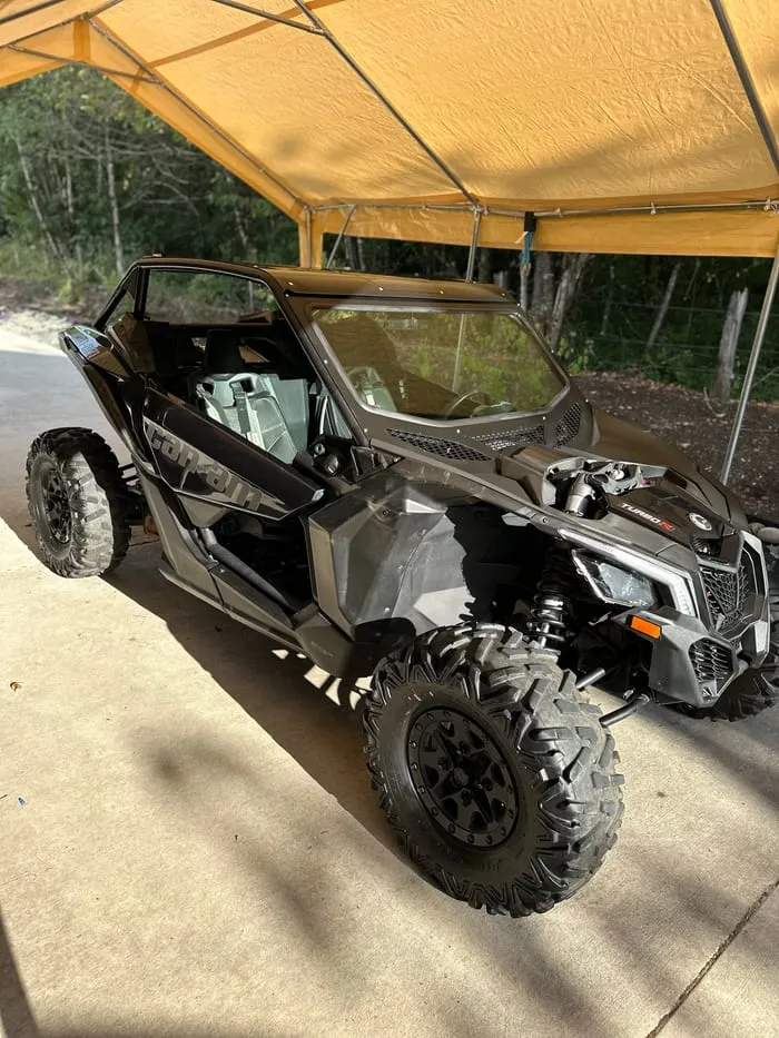 Black Can-Am Maverick side-by-side on knobbly tyres under an open canopy