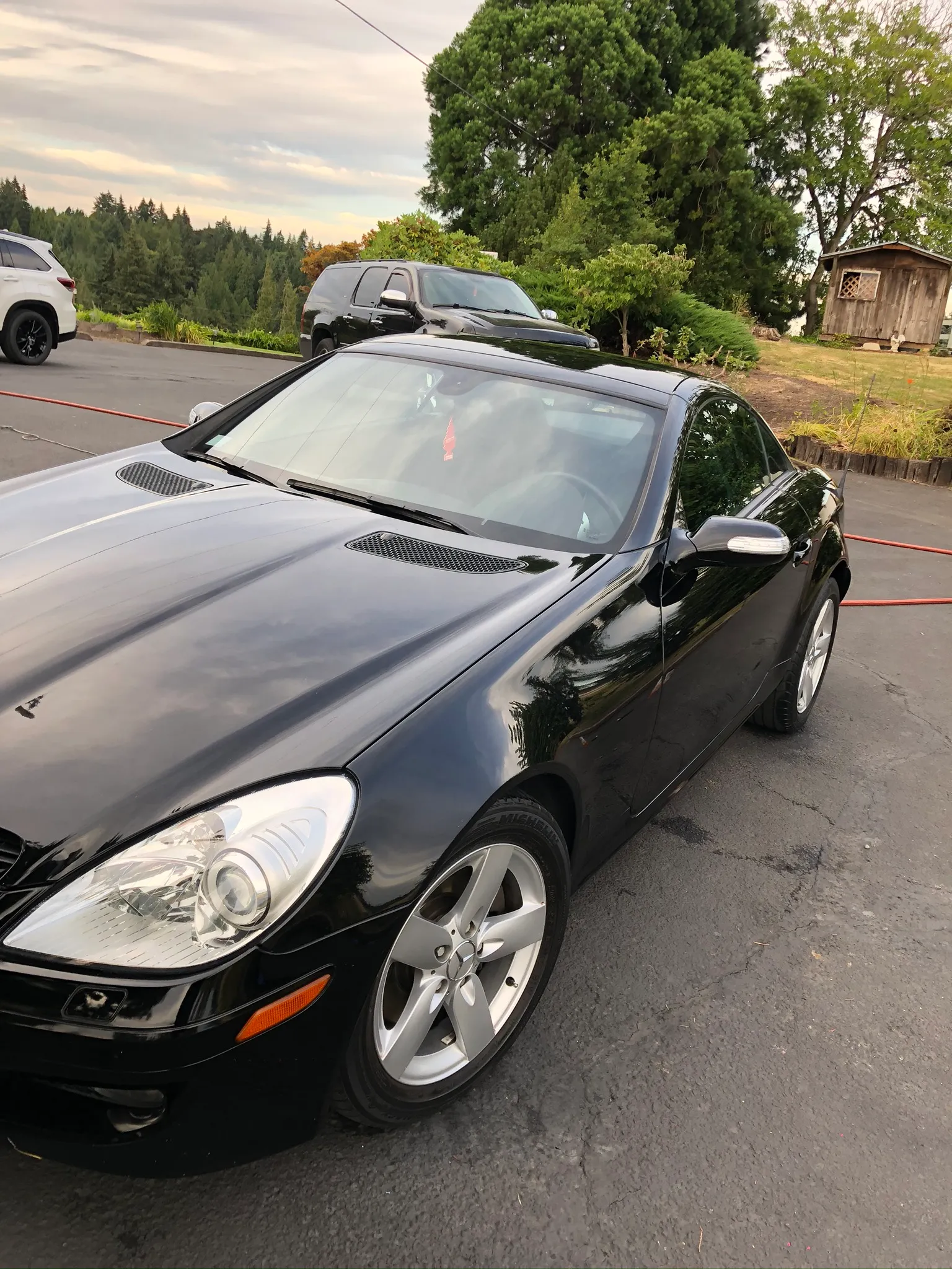 Black Mercedes-Benz SLK roadster outdoors at dusk with a polished finish