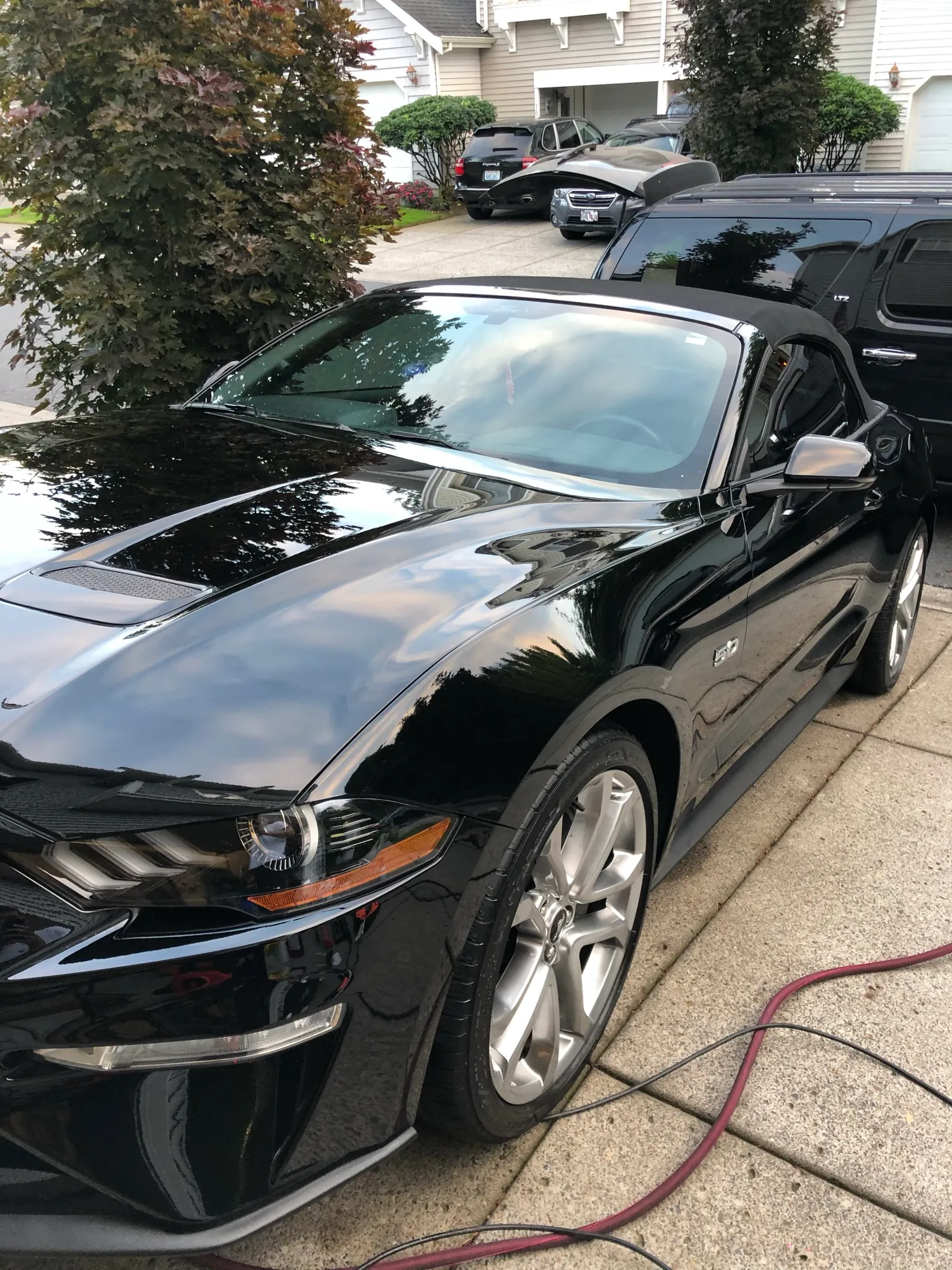 Black Ford Mustang GT convertible detailed at the kerb outside a customer's home