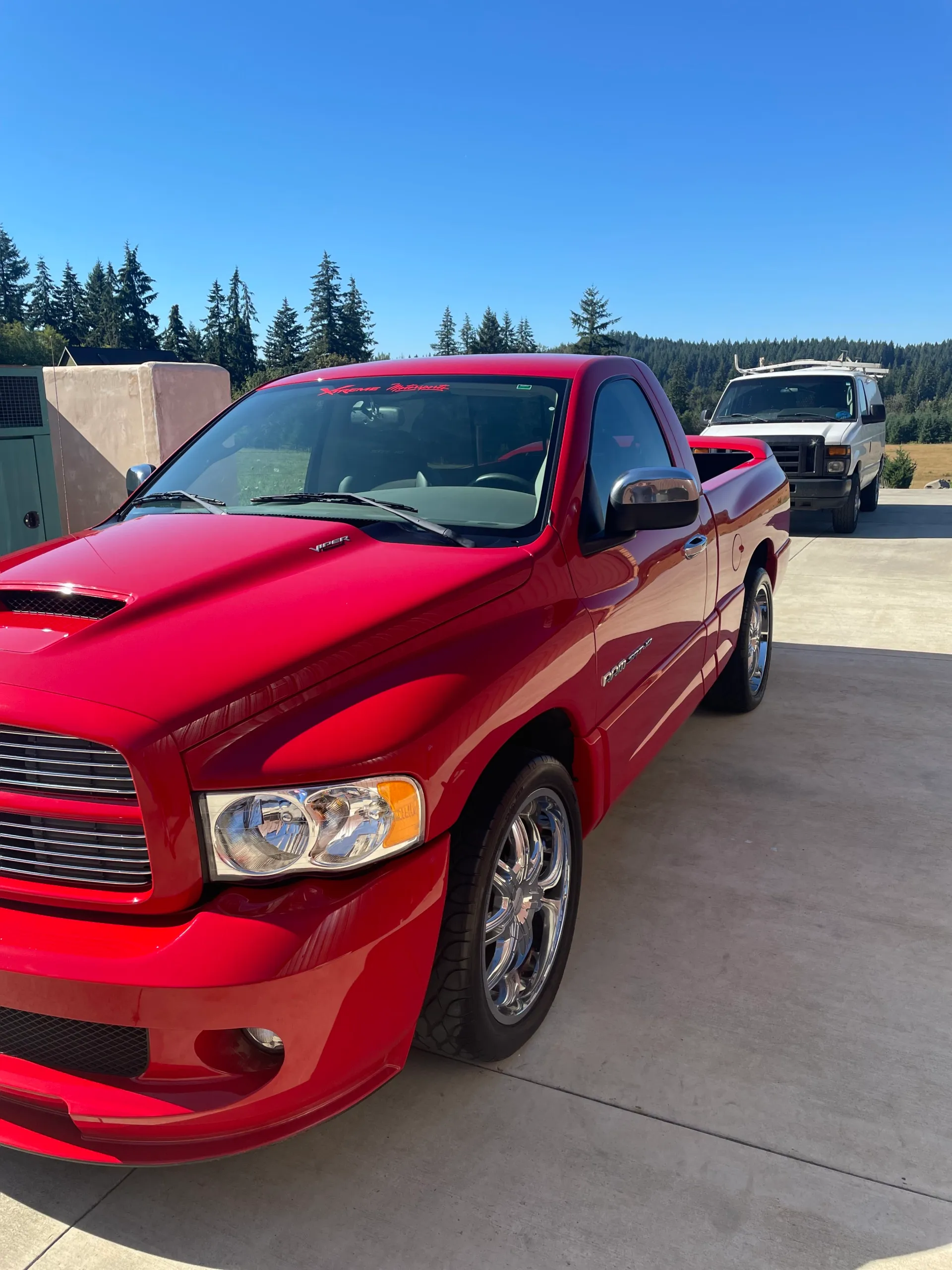 Red Dodge Ram SRT-10 with a high-gloss finish, work van parked behind it