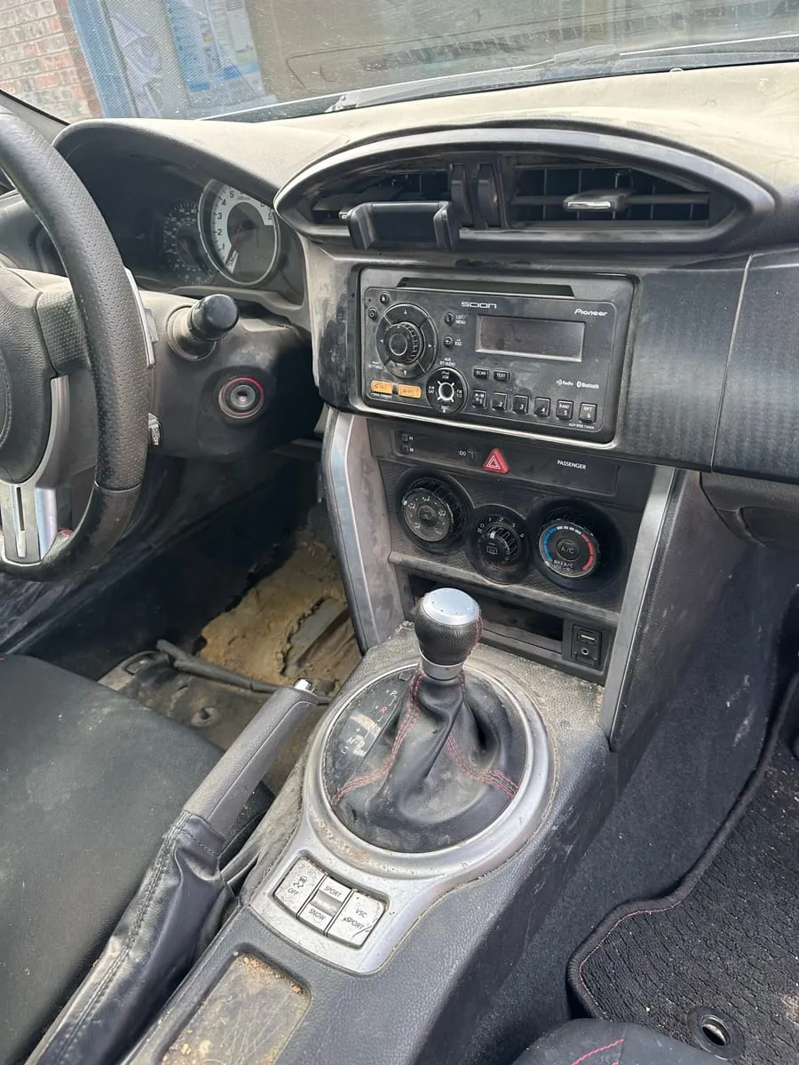 Scion FR-S centre console covered in grey dust, grime packed into the vents, radio buttons and gear surround