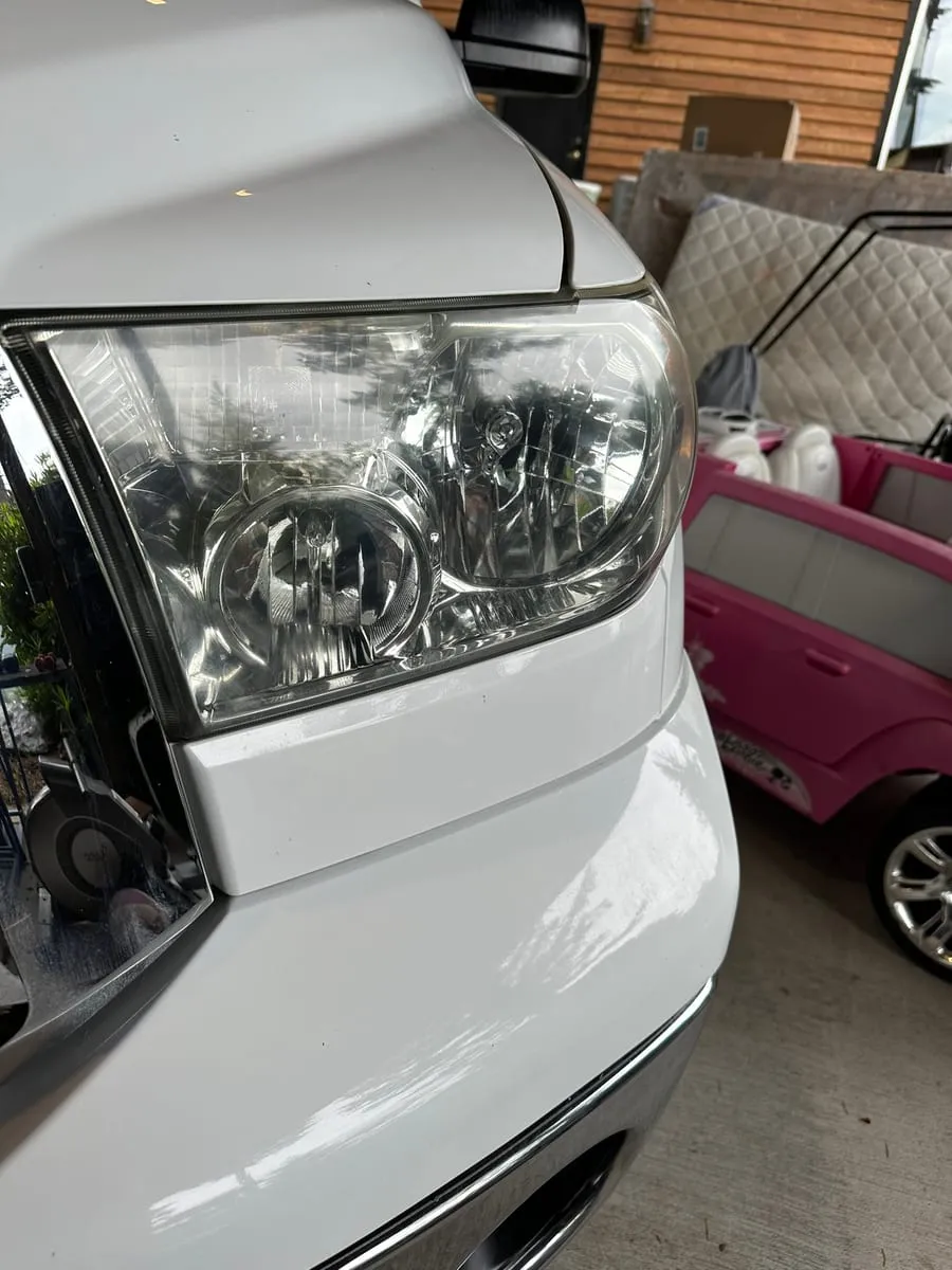 The same Toyota Tundra headlight after restoration, the lens clear and the reflector bowls and bulb sharply visible